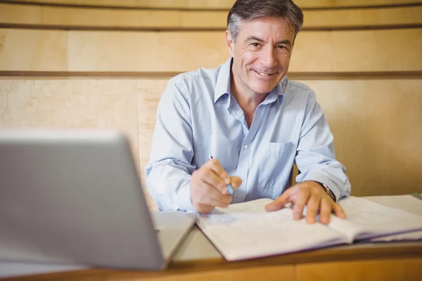 Retrato del profesor feliz escribiendo en un libro en el escritorio — Foto de Stock