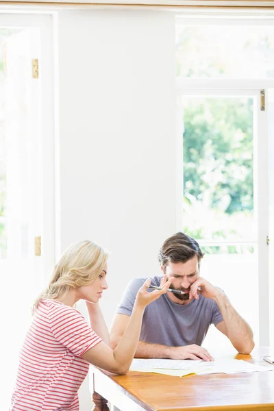 Pareja joven preocupada revisando facturas — Foto de Stock