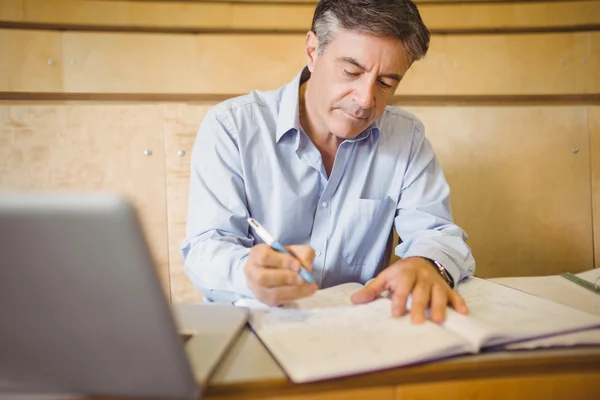 Professor schrijven in boek bij Bureau — Stockfoto