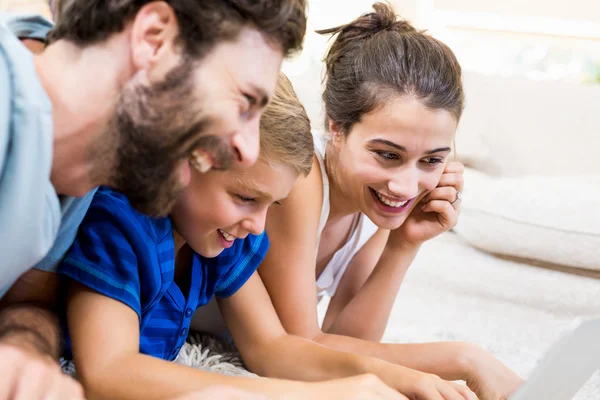 Parents et fils couchés sur un tapis et utilisant un ordinateur portable — Photo