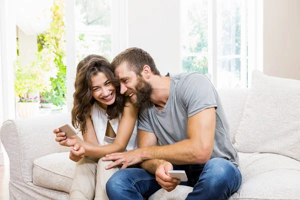 Улыбающаяся молодая пара смотрит на мобильный телефон — стоковое фото