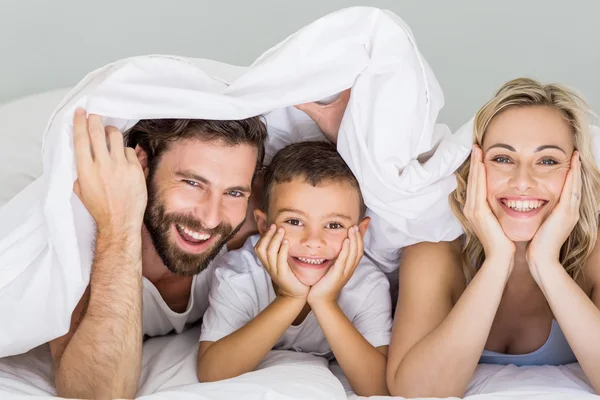 Портрет родителей и сына лежащих на кровати в спальне — стоковое фото