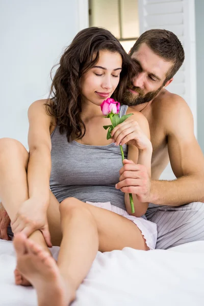 Чоловік пропонує троянду жінці на ліжку — стокове фото