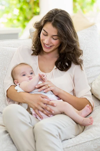 Bebeğini kucağına oturma odasında tutan anne — Stok fotoğraf