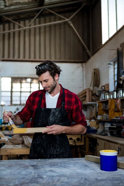 Falegname dipingere un pezzo di legno — Foto Stock