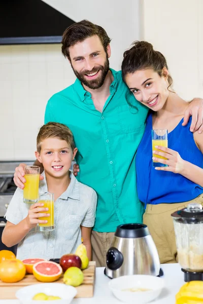 Família segurando suco na cozinha — Fotografia de Stock