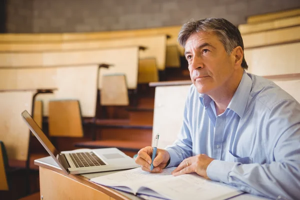 Nachdenklicher Professor schreibt Buch am Schreibtisch — Stockfoto