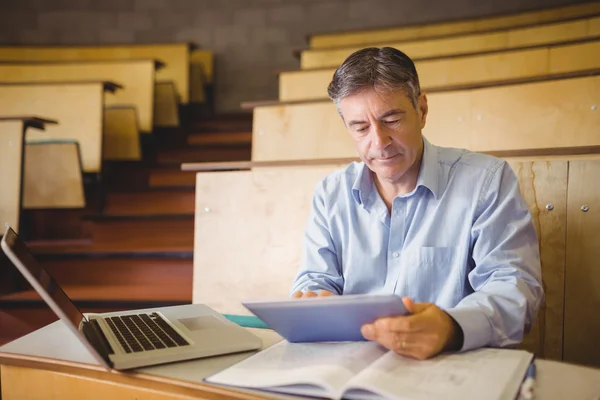 Professor sitter vid skrivbord med digital tablet — Stockfoto