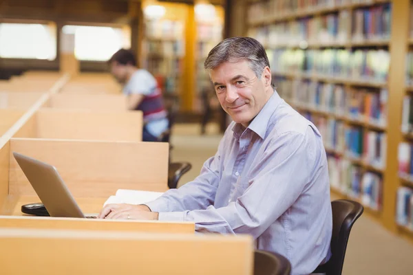 Portret van gelukkig professor zit aan bureau met behulp van zijn laptop — Stockfoto