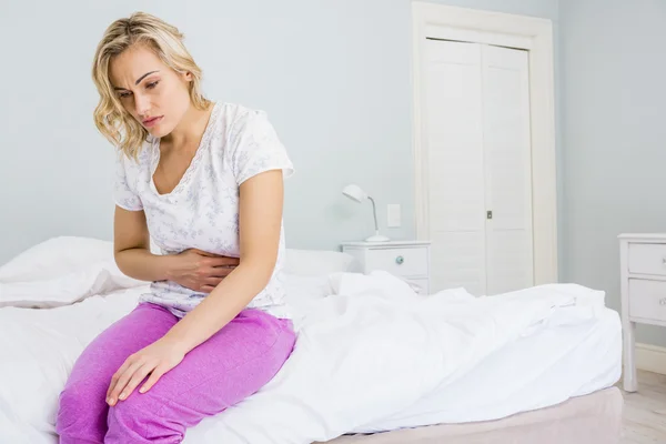 Jonge vrouw met buikpijn in bed — Stockfoto