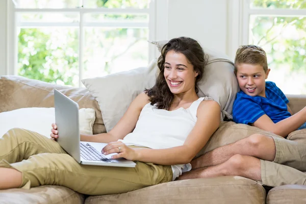 Mor och son sitter på soffan och använder bärbar dator — Stockfoto