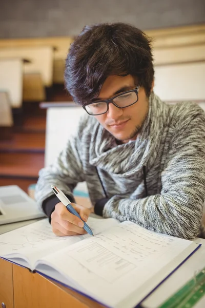 Jovem estudante sentado na mesa leitura notas — Fotografia de Stock