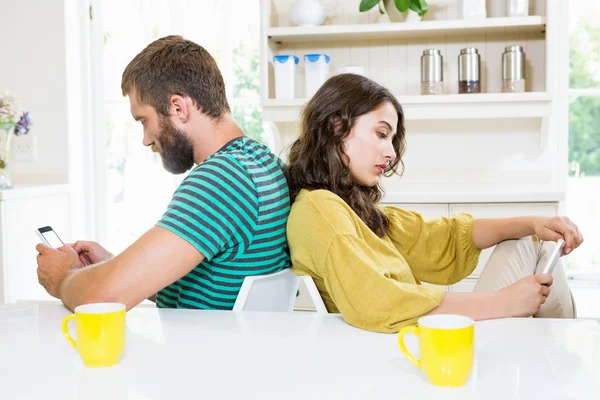 Paret sitter rygg mot rygg och text jävlas på mobiltelefon — Stockfoto