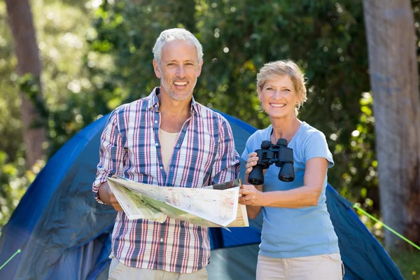 Älteres Paar lächelt und hält Fernglas und Karte in der Hand — Stockfoto