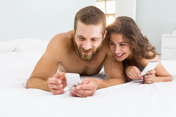 Homem mostrando móvel para mulher na cama — Fotografia de Stock