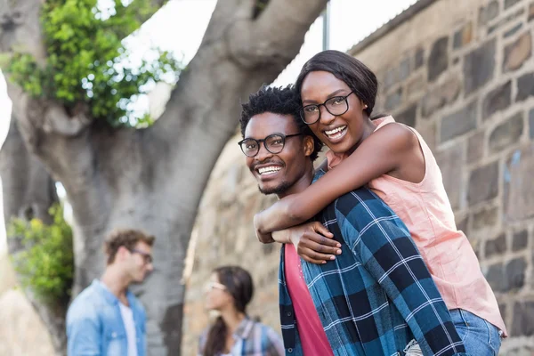 Joven hombre dando piggyback a la mujer — Foto de Stock