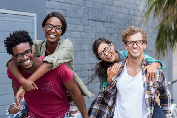 Young men giving piggyback to women — Stock Photo, Image