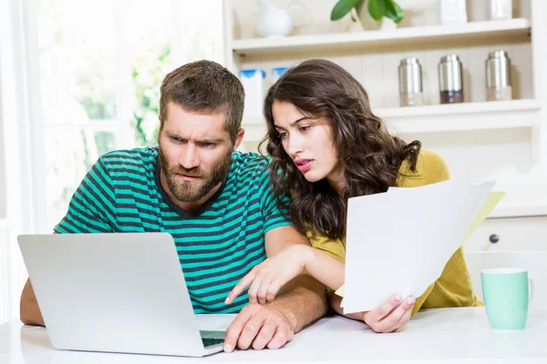 Paret betalar sina räkningar med laptop i köket — Stockfoto