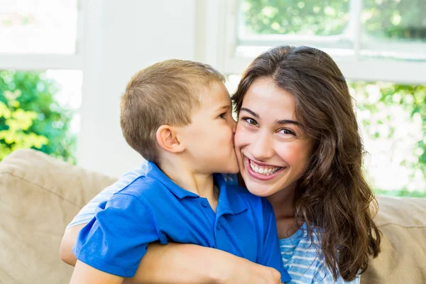 Filho beijando sua mãe na sala de estar — Fotografia de Stock