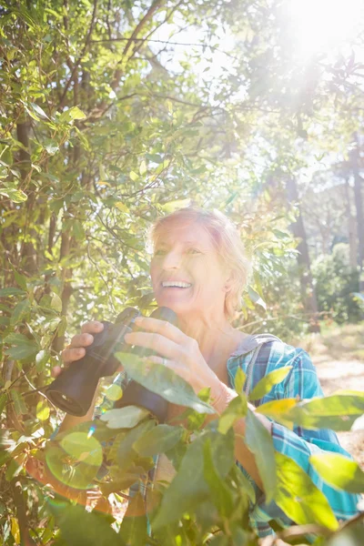 Mature woman smiling and holding binoculars — Stock Photo, Image