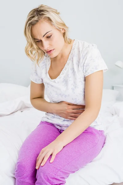 Jonge vrouw met buikpijn in bed — Stockfoto