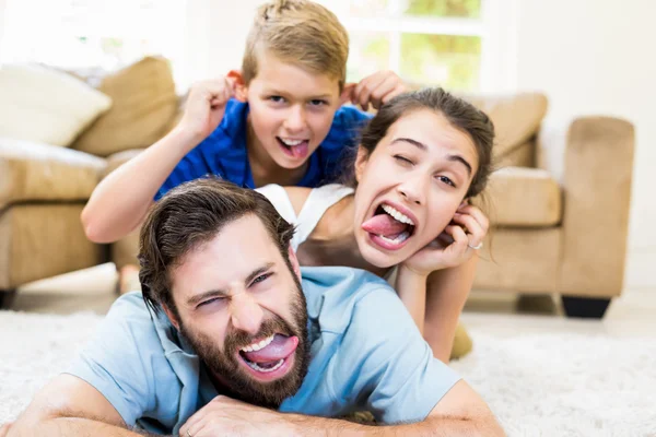 A szülők és a fia feküdt a szőnyeg és a szórakozás portré — Stock Fotó