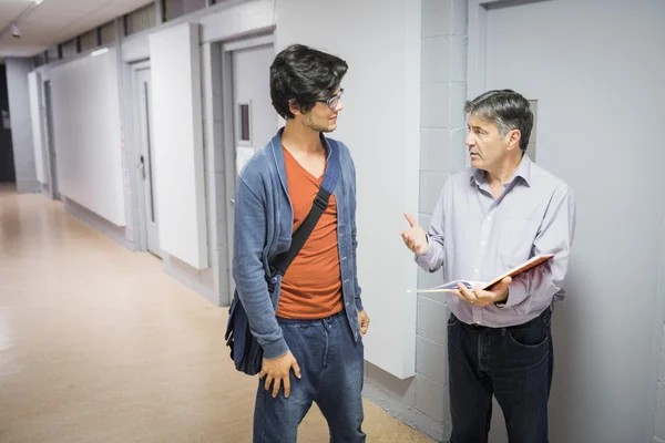 Profesor con cuaderno hablando con un estudiante — Foto de Stock