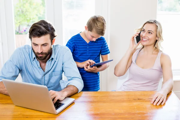 Ouders en zoon met behulp van een laptop, tablet en telefoon — Stockfoto