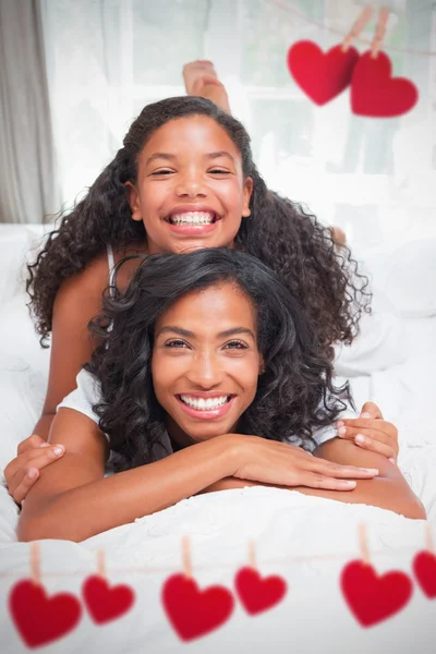 Madre e hija sonriendo y acostadas en la cama — Foto de Stock