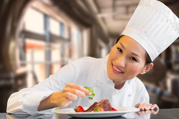 Smiling female chef garnishing food in kitchen — Stock Photo, Image