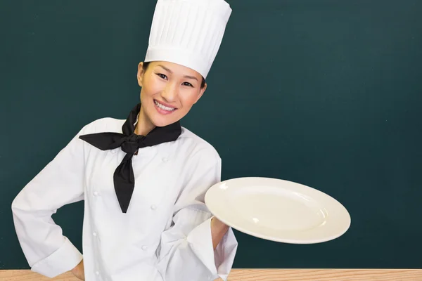 Boş plaka tutarak gülümseyen kadın aşçı — Stok fotoğraf