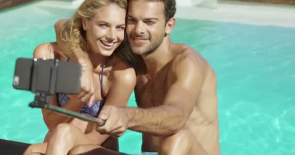 Atractiva pareja tomando selfie junto a la piscina — Vídeos de Stock