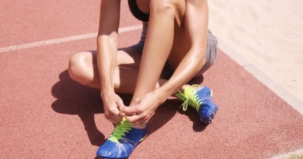 Sportswoman legando i lacci delle scarpe mentre seduto — Video Stock
