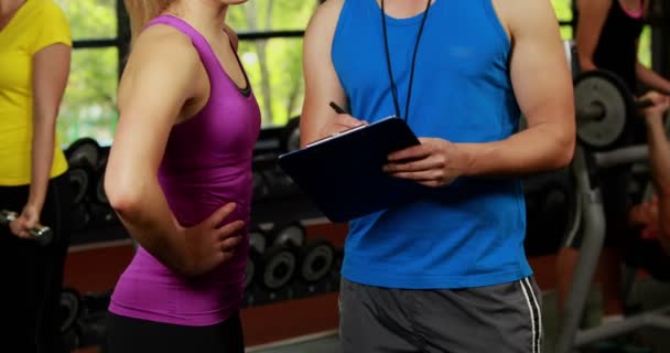 Male trainer helping blonde woman with performance — Stock Video