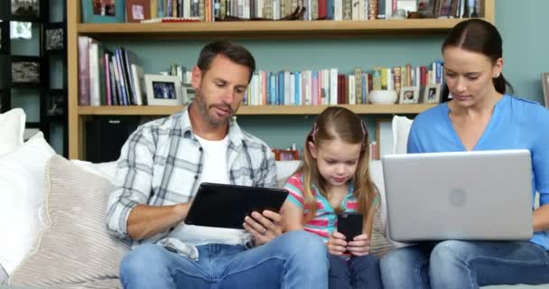 Famiglia che utilizza tecnologie sedute sul divano — Video Stock