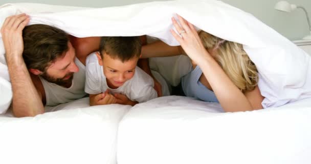 Familia jugando juntos en una cama — Vídeo de stock