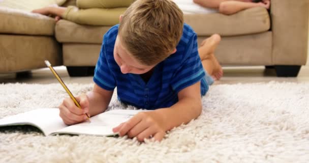 Niño acostado en el suelo dibujo sobre papel — Vídeos de Stock