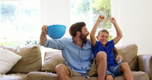 Vader en zoon genietend van voor de televisie — Stockvideo