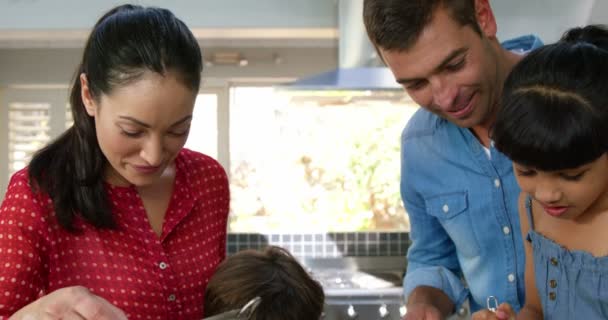 Милая семья готовит торт — стоковое видео