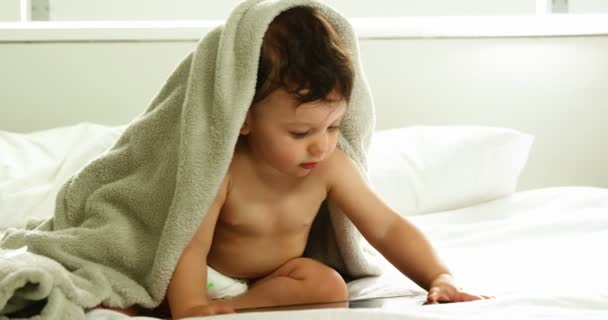 Ребенок с одеялом на голове играет с планшетом — стоковое видео