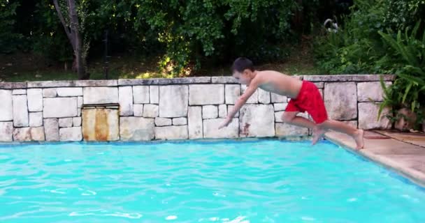 Ребенок в красных купальниках, прыгающий в бассейн — стоковое видео