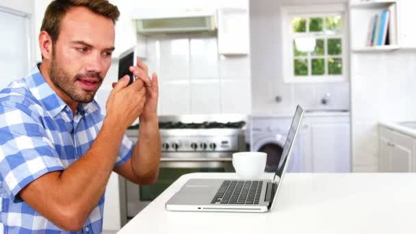 Homem concentrado olhando para laptop e telefonema — Vídeo de Stock