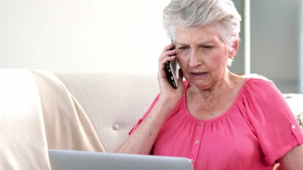 Vieja en un teléfono con su computadora — Vídeos de Stock