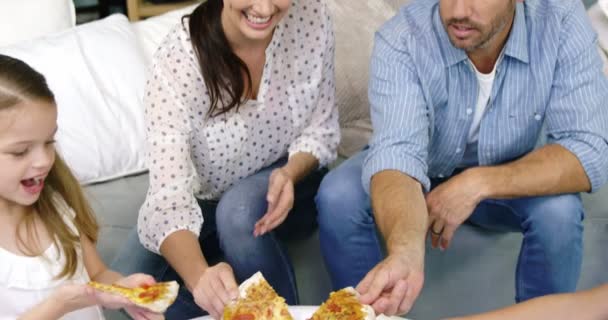 Familia de cuatro comiendo una pizza juntos — Vídeos de Stock