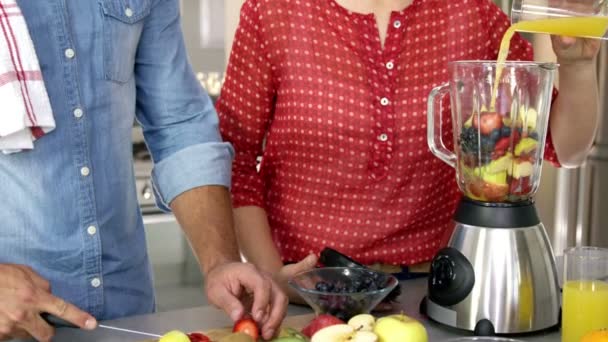 Pareja preparando zumo de frutas en la cocina — Vídeo de stock