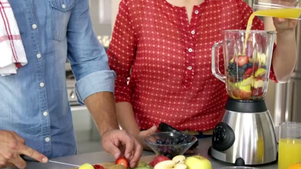 Couple préparant le jus de fruits sur la cuisine — Video