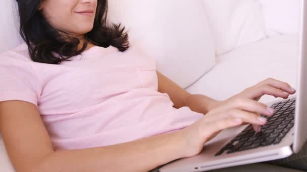 Жінка сидить на дивані, використовуючи свій ноутбук — стокове відео
