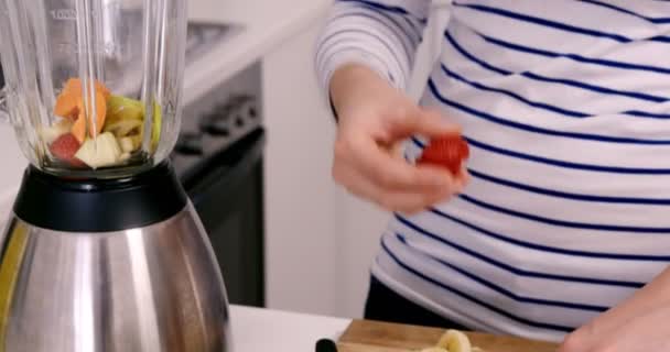 Mujer poniendo frutas en su licuadora — Vídeos de Stock