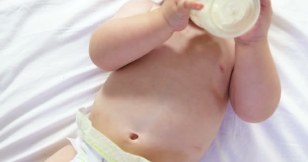 Baby liggen en zijn baby's drinkfles — Stockvideo