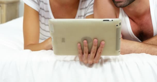 Casal deitado na cama e olhando um tablet — Vídeo de Stock